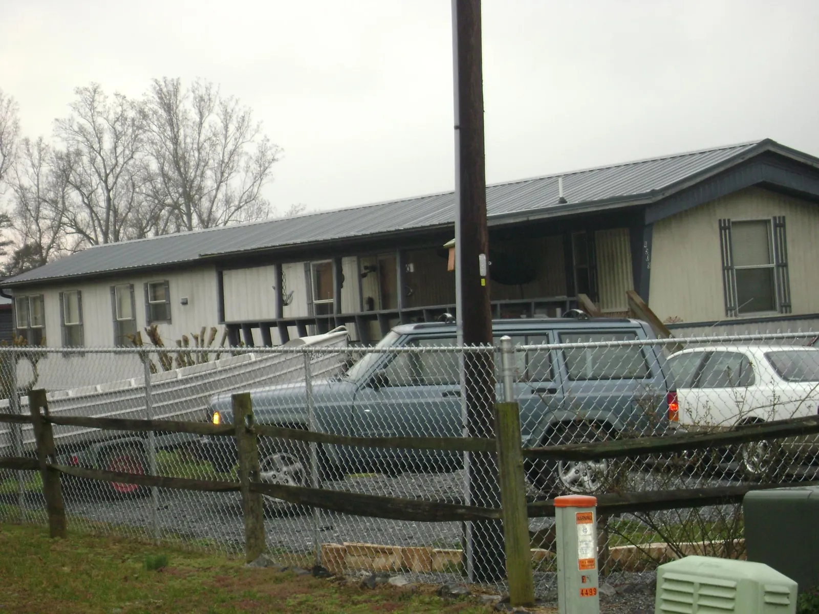 Dark metal roof on a long single story building behind a chain link fence in Greenville